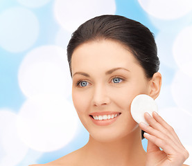 Image showing smiling woman cleaning face skin with cotton pad