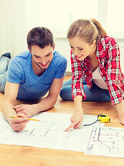 Image showing smiling couple looking at blueprint at home