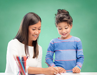 Image showing happy teacher and little school girl drawing