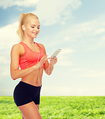 Image showing smiling sporty woman with smartphone and earphones