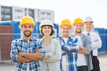 Image showing group of smiling builders in hardhats outdoors