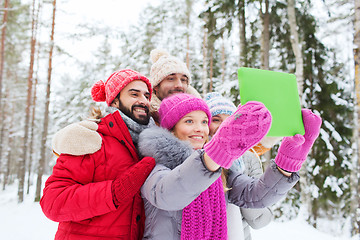 Image showing smiling friends with tablet pc in winter forest