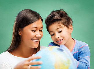 Image showing happy teacher and little school girl with globe