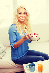 Image showing smiling woman with bowl of muesli having breakfast