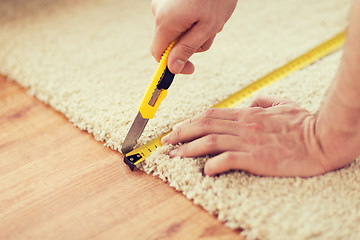 Image showing close up of male hands cutting carpet