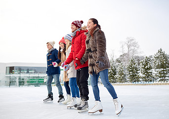 Image showing happy friends ice skating on rink outdoors