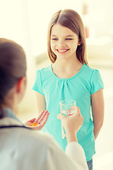 Image showing female doctor giving pills and water to child