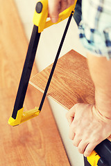 Image showing close up of male hands cutting parquet floor board