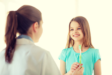 Image showing female doctor giving toothbrush to smiling girl