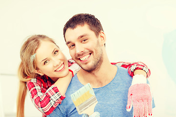 Image showing smiling couple covered with paint with paint brush