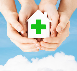 Image showing hands holding paper house with green cross