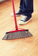 Image showing close up of male brooming wooden floor