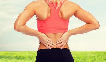 Image showing close up of sporty woman touching her back