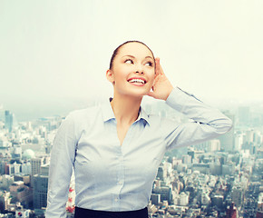 Image showing smiling businesswoman listening gossig