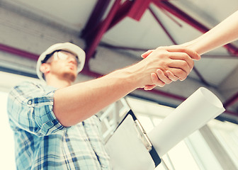 Image showing builder with blueprint shaking partner hand