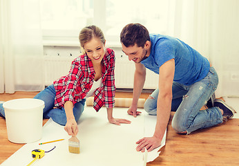 Image showing smiling couple smearing wallpaper with glue