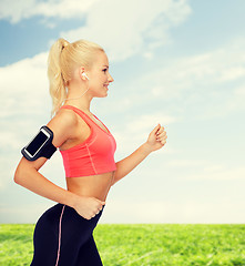 Image showing sporty woman running with smartphone and earphones