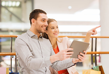 Image showing couple with tablet pc and shopping bags in mall