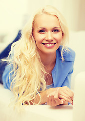 Image showing smiling young woman lying on sofa at home