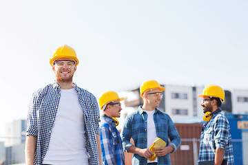 Image showing group of smiling builders in hardhats outdoors