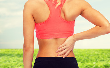 Image showing close up of sporty woman touching her back