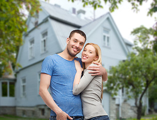 Image showing smiling couple hugging over house background