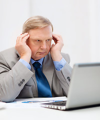 Image showing upset older businessman with laptop in office