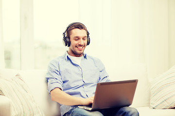 Image showing smiling man with laptop and headphones at home