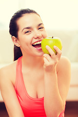 Image showing smiling teenage girl with green apple at home