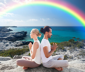 Image showing happy couple meditating in lotus pose on beach