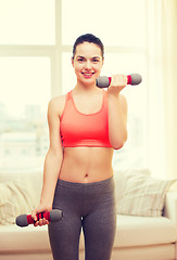 Image showing smiling teenage girl exercising with dumbbells