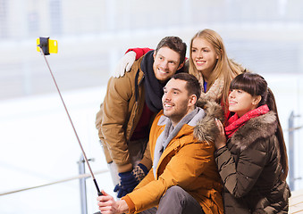 Image showing happy friends with smartphone on skating rink