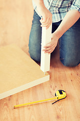 Image showing close up of male hands assemblying legs to table