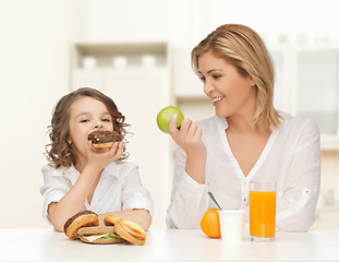 Image showing happy mother and daughter eating breakfast