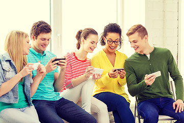 Image showing smiling students with smartphone texting at school