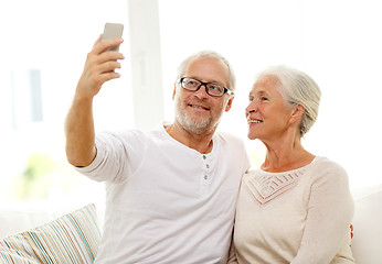 Image showing happy senior couple with smartphone at home