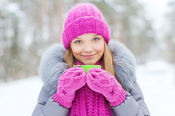 Image showing smiling young woman with cup in winter forest