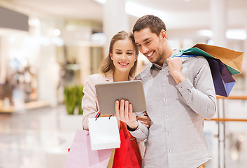 Image showing couple with tablet pc and shopping bags in mall