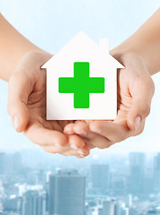 Image showing hands holding paper house with green cross