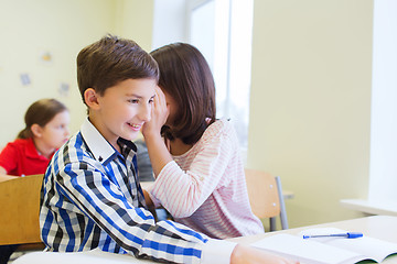 Image showing smiling schoolgirl whispering to classmate ear