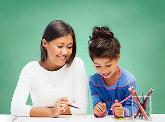 Image showing happy teacher and little school girl drawing