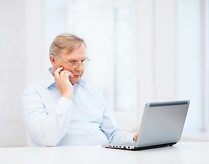 Image showing old man in eyeglasses working with laptop at home