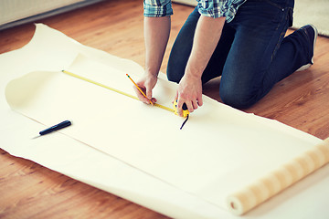 Image showing close up of male hands measuring wallpaper