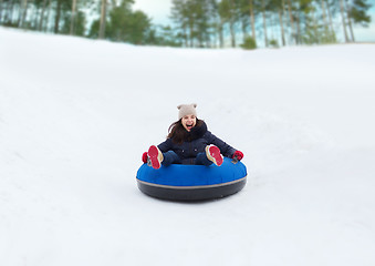 Image showing happy teenage girl sliding down on snow tube