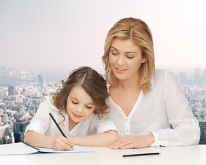 Image showing happy mother and daughter writing in notebook