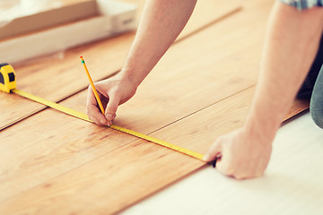 Image showing close up of male hands measuring wood flooring