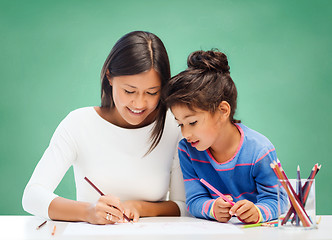 Image showing happy teacher and little school girl drawing