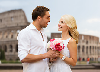 Image showing happy couple with bunch of flowers over coliseum