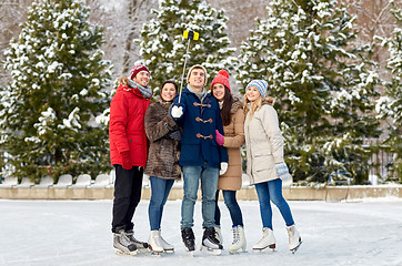 Image showing happy friends with smartphone on ice skating rink
