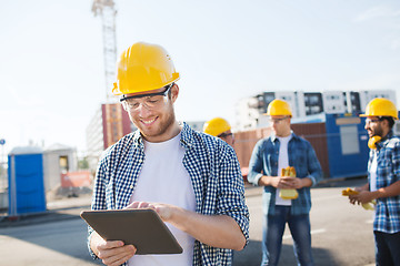 Image showing smiling builders in hardhats with tablet pc